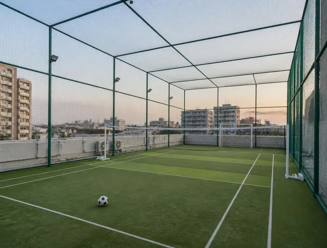Floodlit sports practice net enclosure with green netting
